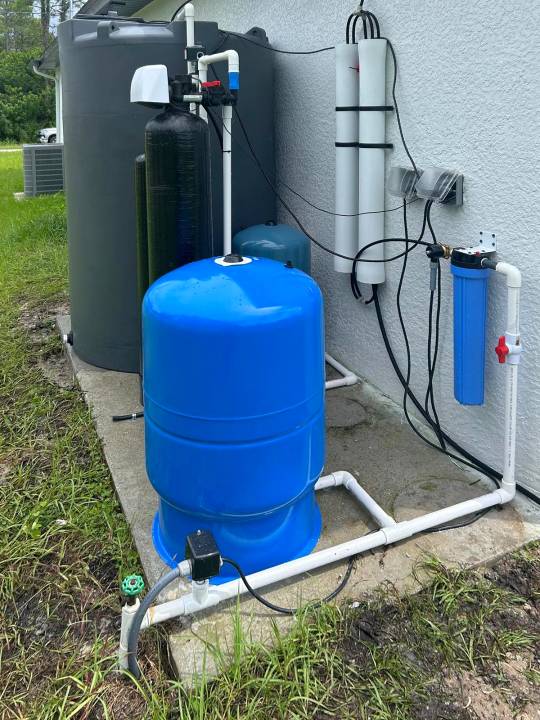 Side yard installation with a blue pressure tank and wall mounted membranes